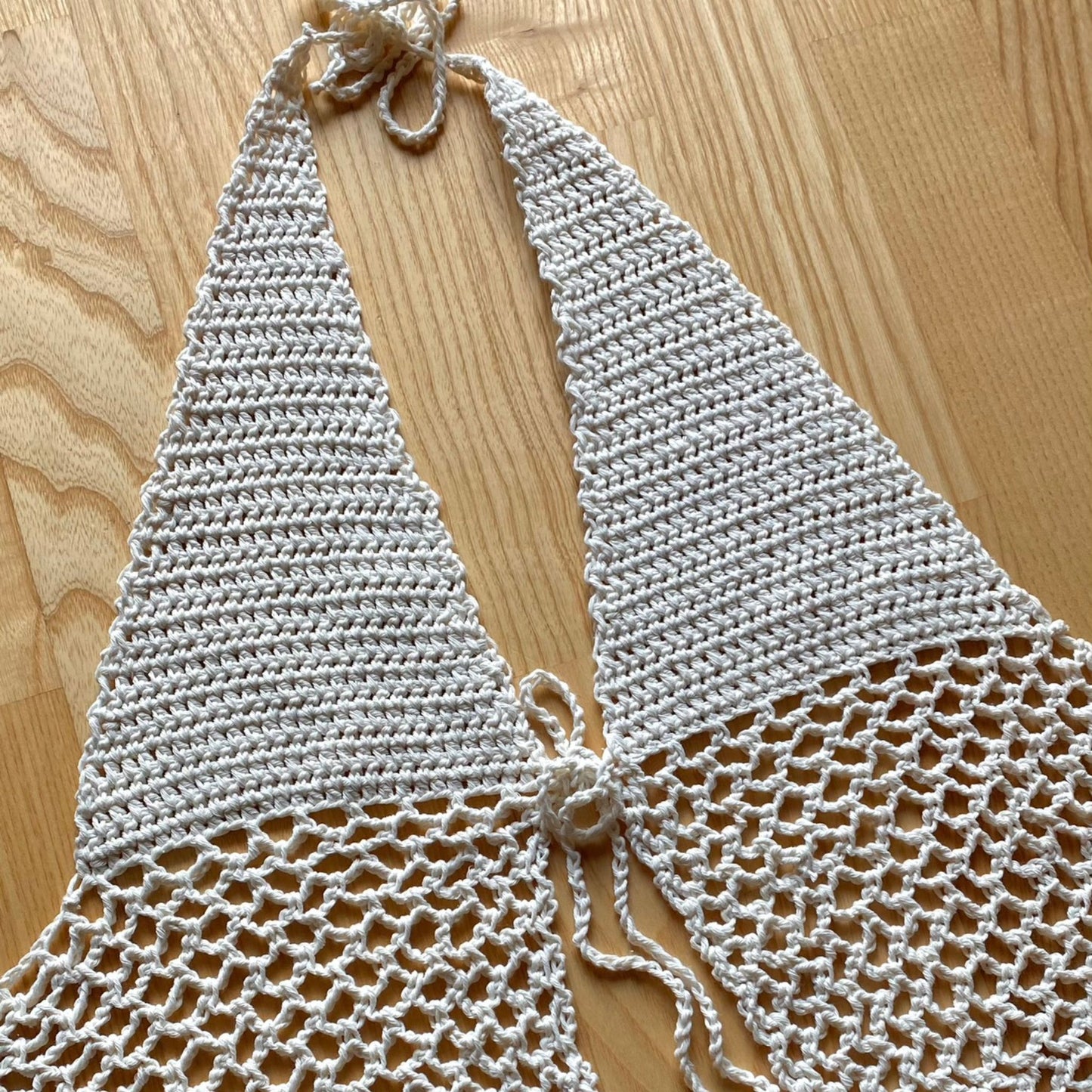 Hvid hæklet halter top med gennemsigtige mesh paneler og en sløjfe i nakken og under brystet