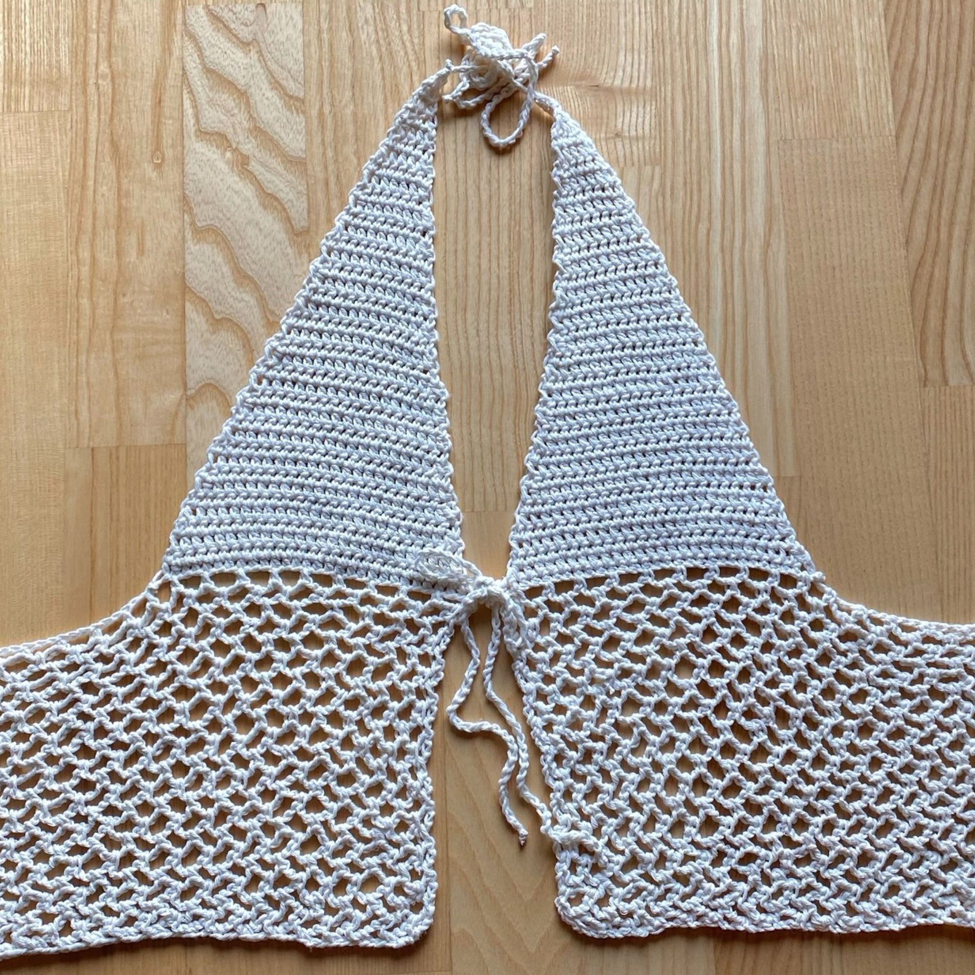 White crochet halter neck top displayed flat on wooden floor