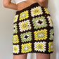 Girl posing in a brown, green, yellow and white crochet granny square skirt