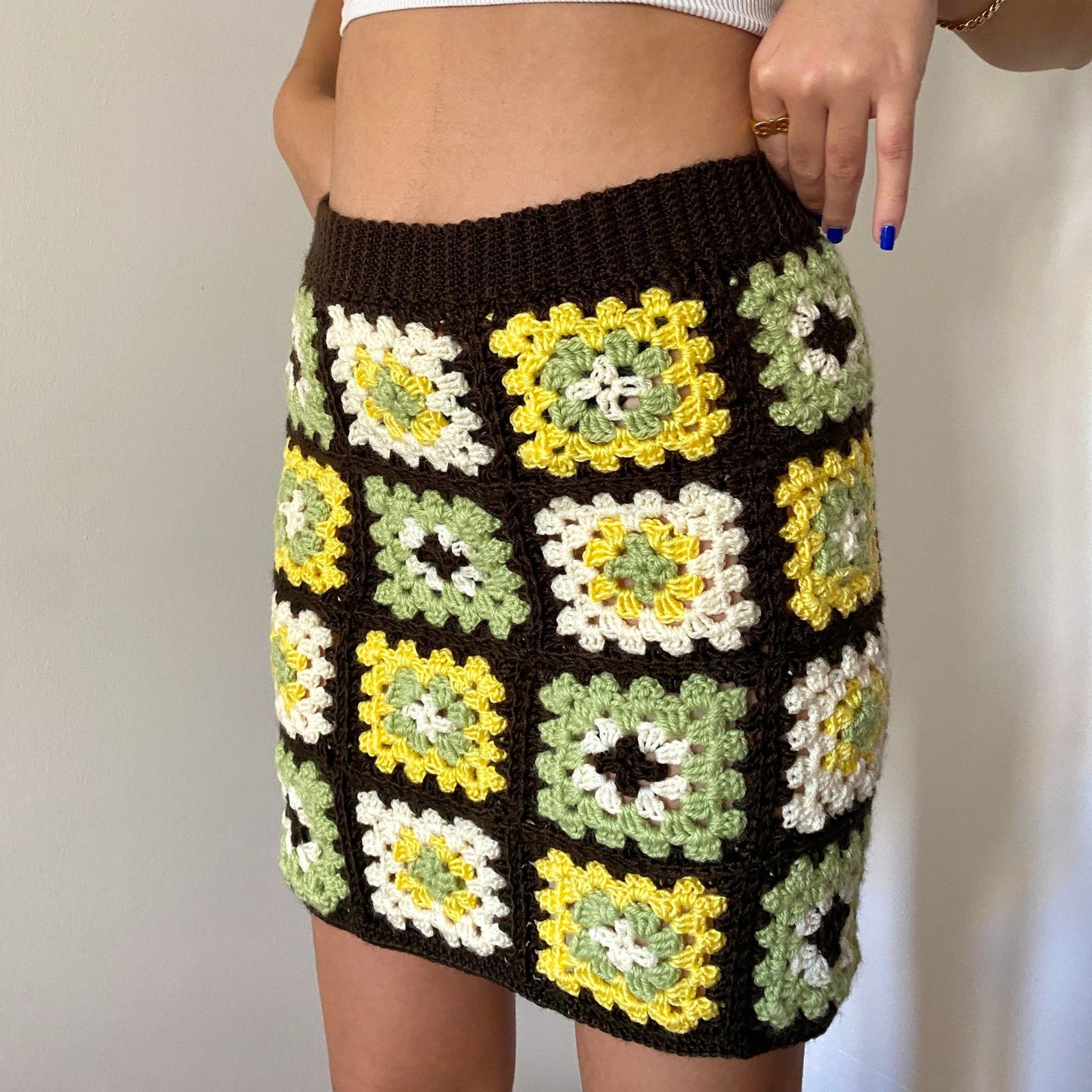Girl posing in a brown, green, yellow and white crochet granny square skirt