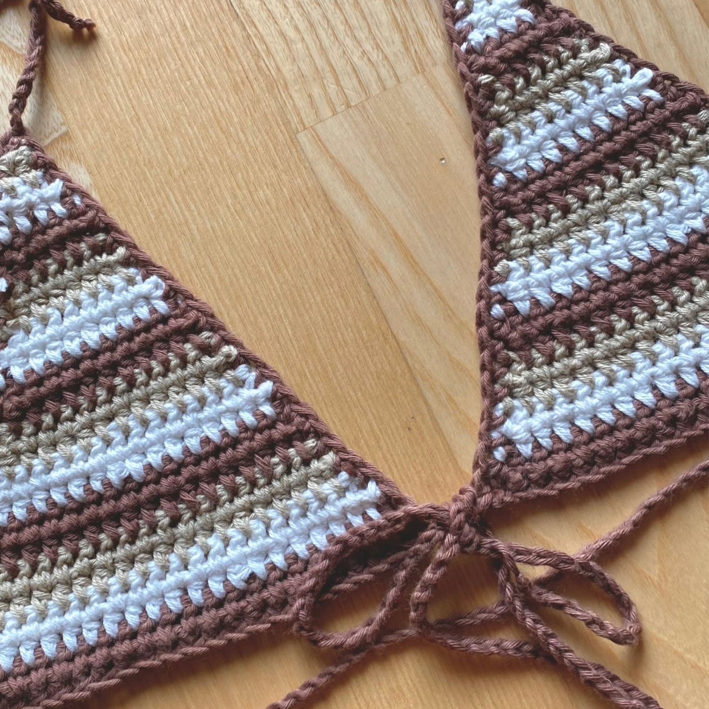 Girl posing in a brown, beige and white striped crochet triangle bikini top that ties around the neck and in the front under the breast